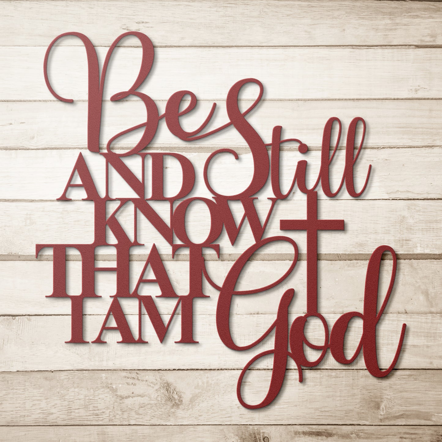 The "Be Still And Know Christian Metal Art" is expertly crafted from 18 gauge steel and displays bold red text that reads, "Be Still and Know That I Am God," alongside a cross symbol. It is elegantly mounted on a light wooden background, making it an ideal piece for enhancing your home decor.