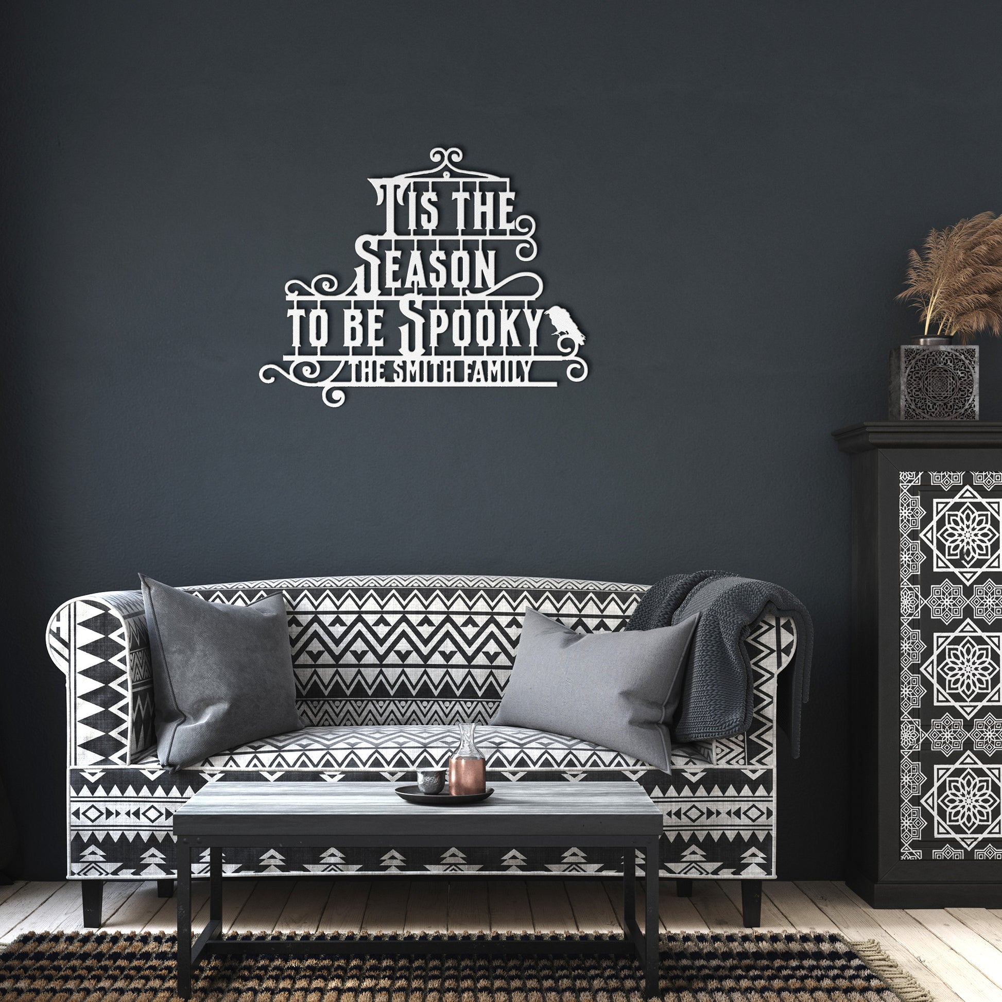 A brick wall with a wooden arched door and a Custom Halloween Metal Sign reading "Tis the season to be spooky." A potted plant with white flowers is placed on the left side of the door.