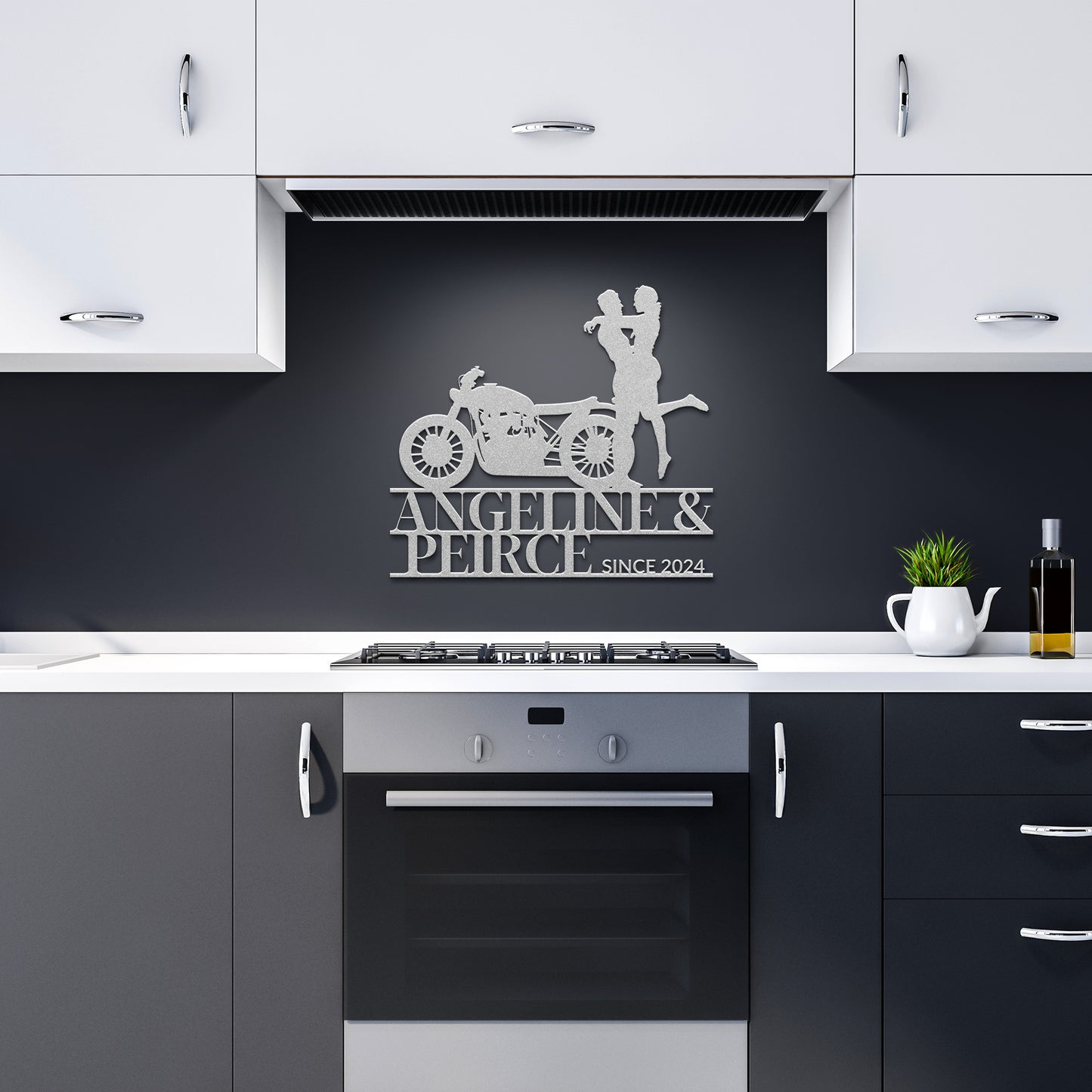 A modern kitchen with white upper cabinets and dark lower cabinets features a stunning oven centered below the Custom Motorcycle Couple Metallic Wall Art. This unique piece of home decor, showcasing a couple with a motorcycle, is labeled "Angelina & Peirce, since 2024.