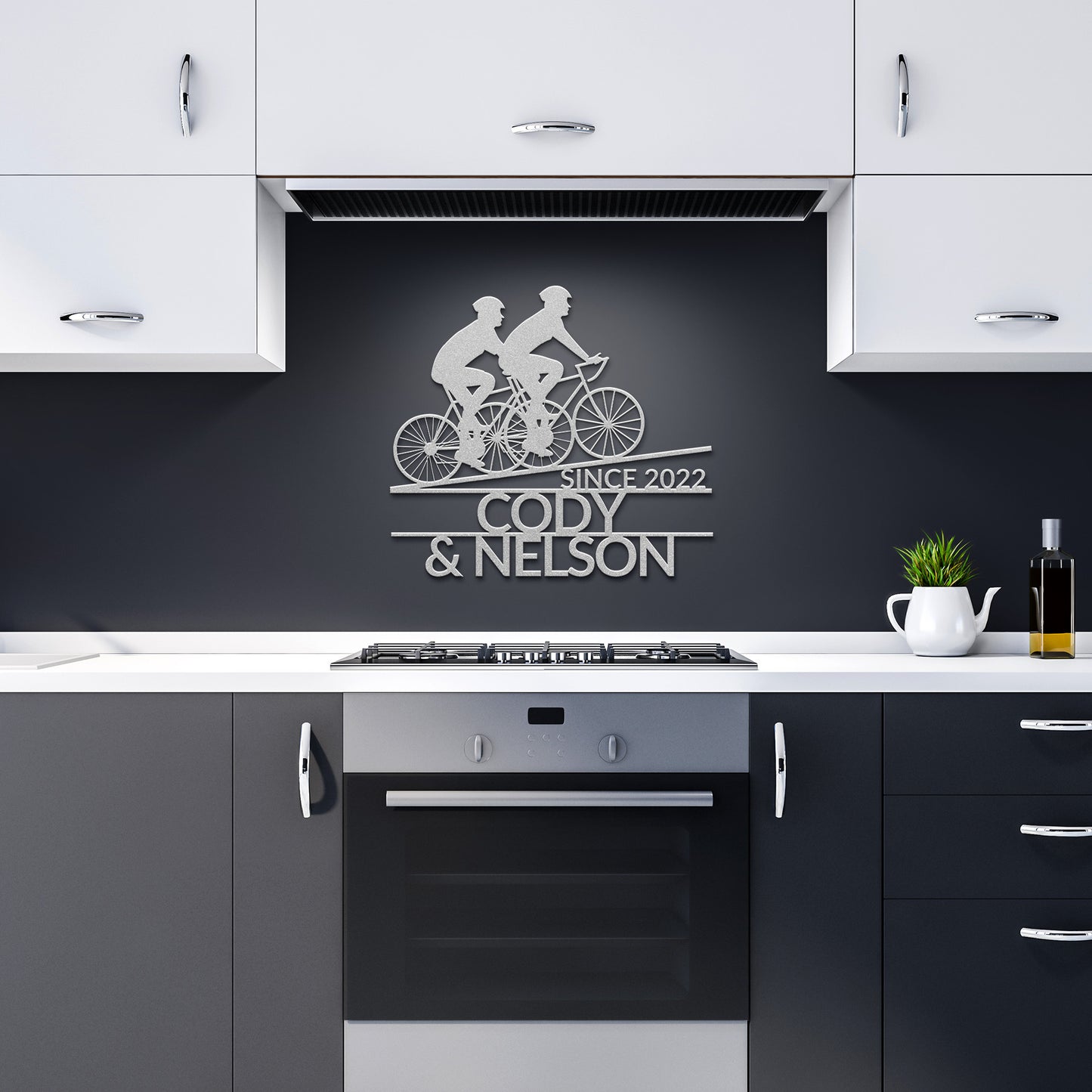 A contemporary kitchen with a combination of white and dark cabinetry is enhanced by the sleek "Custom Riding Buddies Metal Sign," featuring two cyclists and the inscription "Since 2022 Cody & Nelson" mounted above the stove.