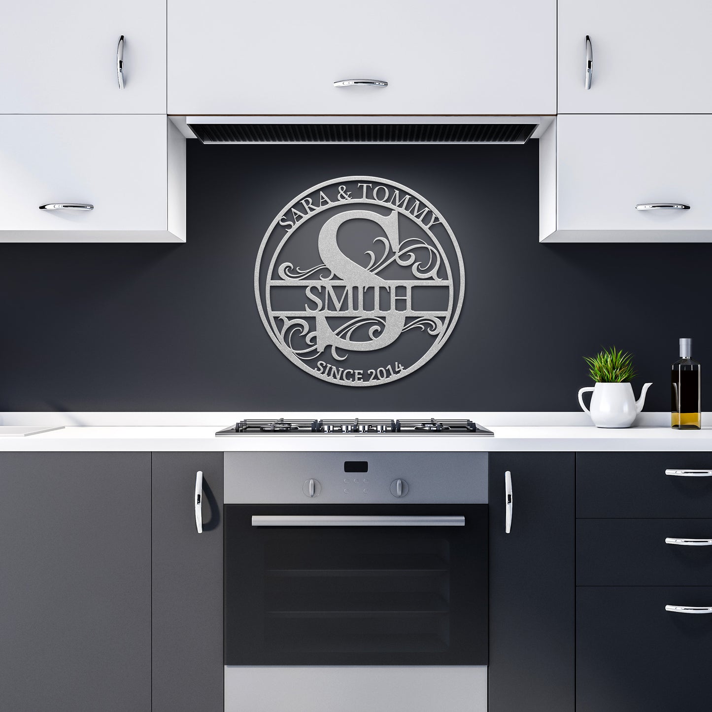 Modern kitchen with white cabinets and a stainless steel oven. Above the oven, a Custom Round Personalized Metal Monogram Sign crafted from 18 gauge steel displays "Sara & Tommy Smith, Since 2024." A plant and oil bottle add style to the counter.