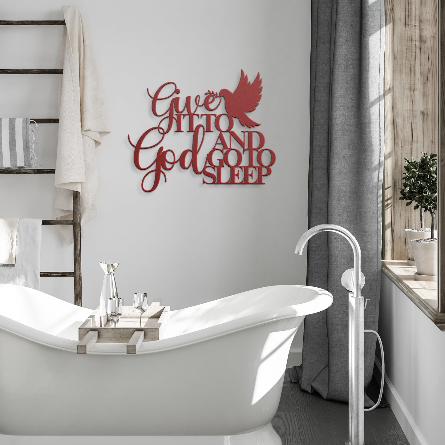 A modern bathroom with a freestanding white bathtub, a ladder shelf with towels, and the "Give It To God And Go To Sleep Christian Metal Sign" featuring red lettering on the wall.
