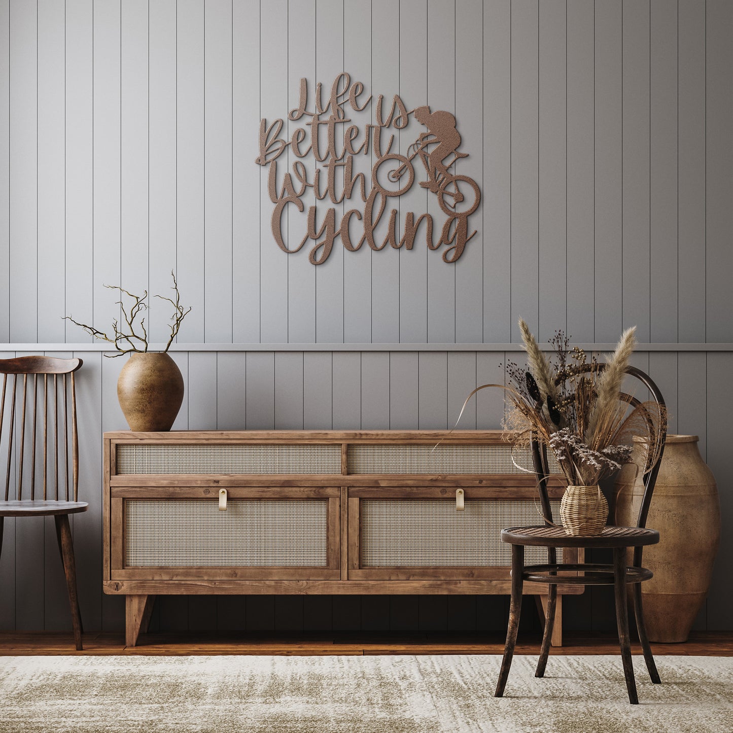 A brick wall with a wooden door, a durable Life Is Better With Cycling Metal Art sign, an exterior light, and a small potted plant with white flowers.