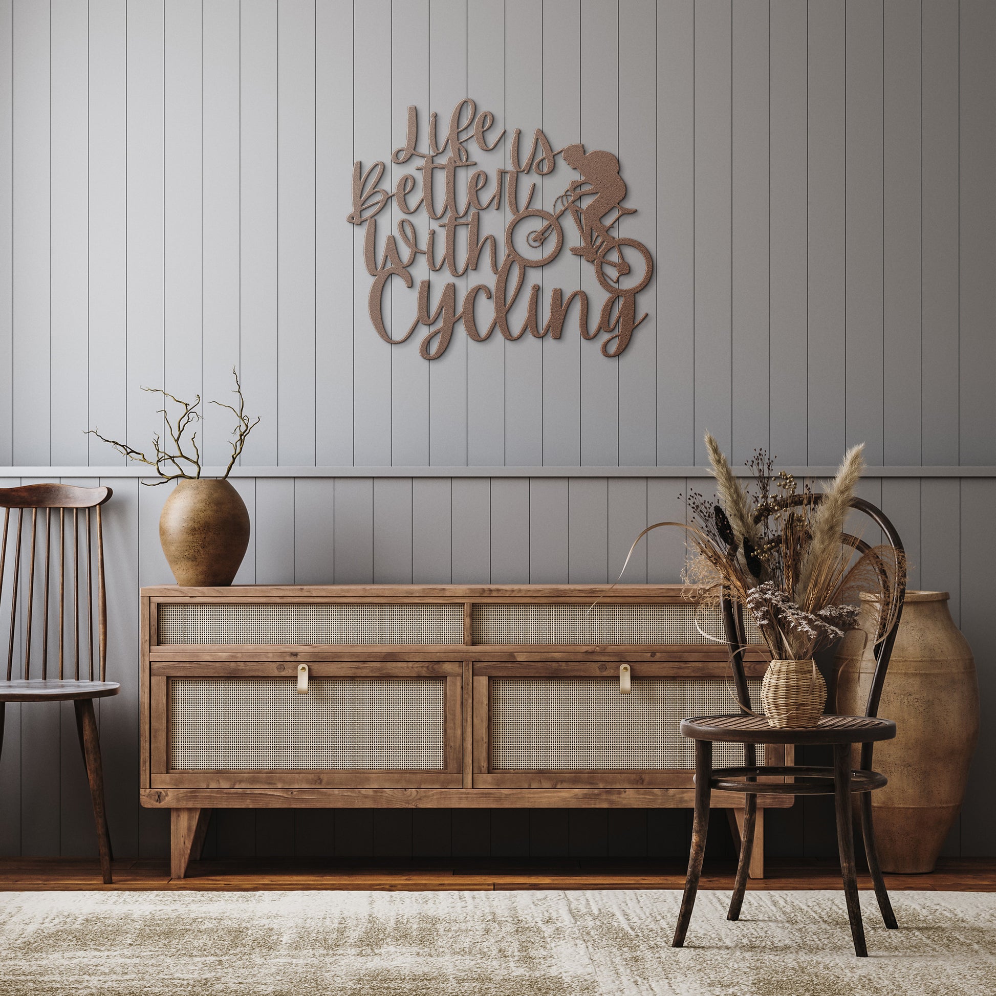 A brick wall with a wooden door, a durable Life Is Better With Cycling Metal Art sign, an exterior light, and a small potted plant with white flowers.