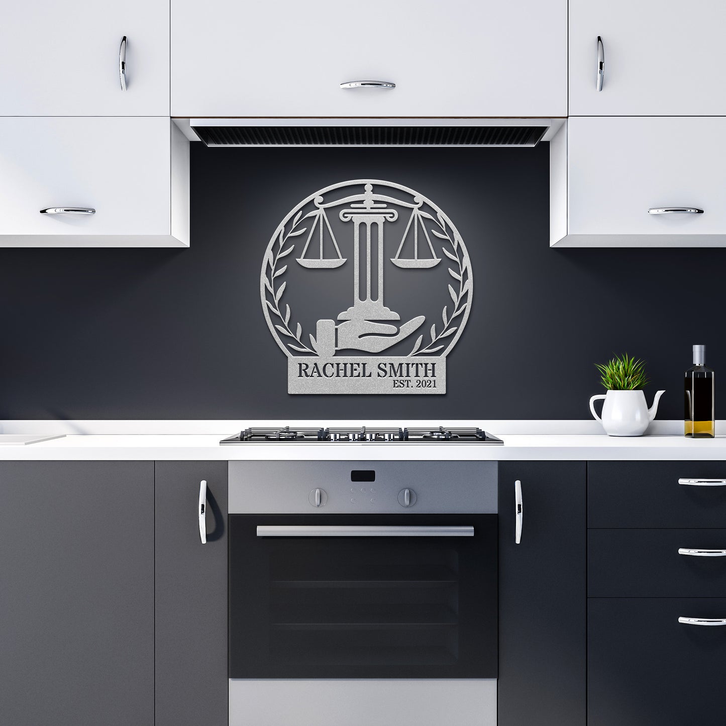A modern kitchen features gray cabinets, a stainless steel oven, and the Scales of Justice Metallic Wall Art crafted from 18-gauge steel. This stylish metal sign displays the scales of justice and the inscription "Rachel Smith Est. 2021," offering a personalized touch to the home decor.