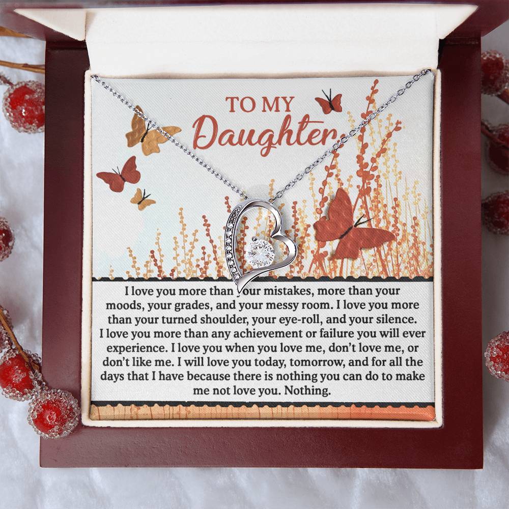 The Daughter-Love You More - Forever Love Necklace, featuring a shimmering CZ crystal and an elegant gold finish, is beautifully presented on a card decorated with butterflies and flowers, conveying a heartfelt message to a daughter.