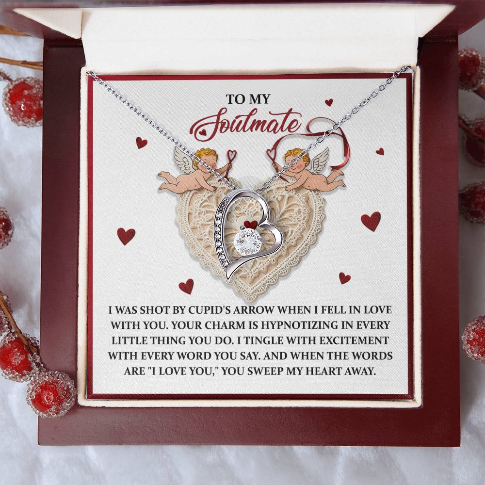 The Soulmate-Sweep My Heart - Forever Love Necklace showcases a heart-shaped charm with cherub designs, adorned with a stunning CZ crystal and lustrous gold finish. The included card shares a romantic message about falling in love and being captivated by your soulmate.