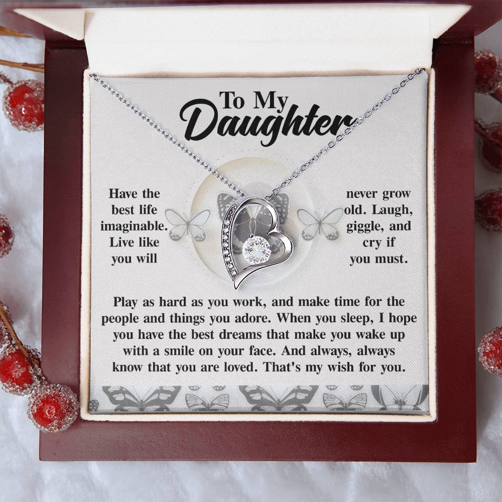 The Daughter-My Wish - Forever Love Necklace, featuring a silver heart charm and CZ crystal accents, elegantly conveys a heartfelt message that encourages a daughter to live fully, find joy, and feel loved. The addition of a white gold finish enhances the elegance of this meaningful piece.