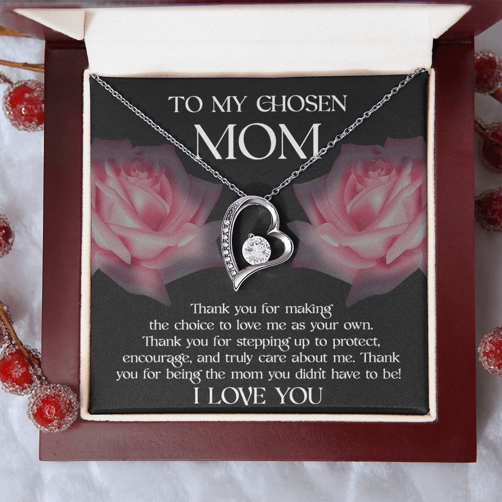 The "To Bonus Mom, My Chosen Mom - Forever Love Necklace" features a silver heart-shaped pendant and comes in an open gift box. Inside the lid is a heartfelt message expressing love and gratitude to a chosen mother, set against a background adorned with rose graphics. Ideal for Mother's Day, this necklace is available in either white gold or yellow gold finish.