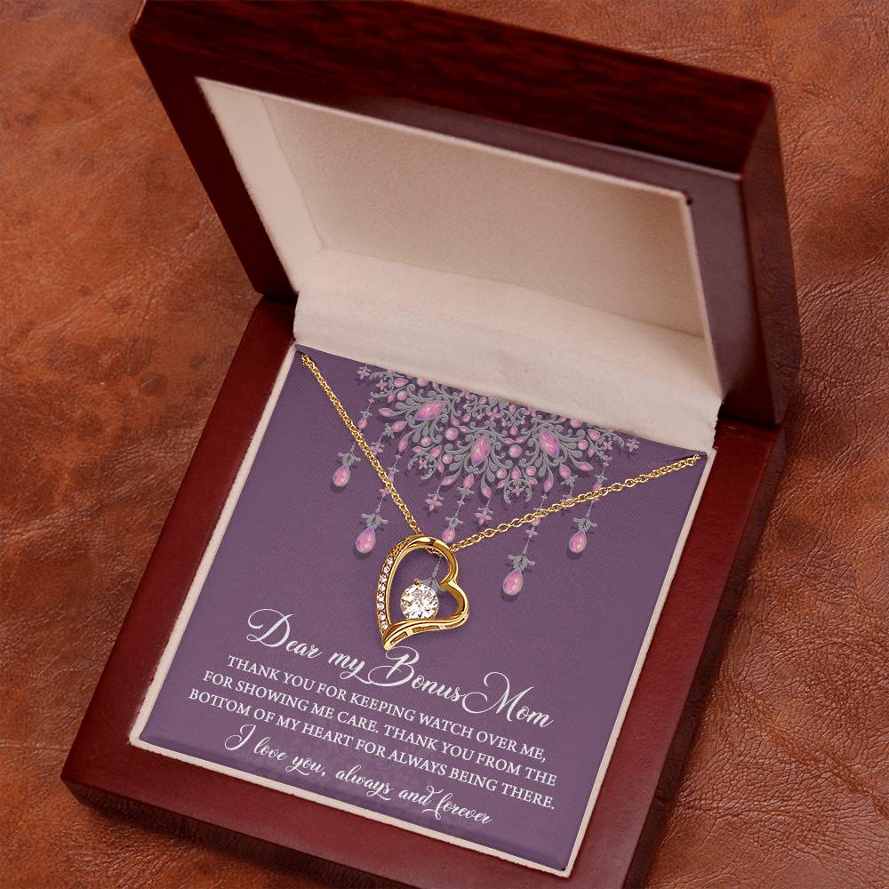 A "To Bonus Mom, Always Being There - Forever Love Necklace" with an intertwined heart and circle pendant is displayed in an open wooden jewelry box, its white gold finish gleaming beside a message on the card inside.