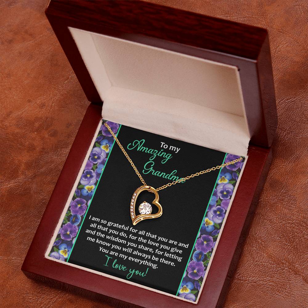 The "To Grandma, My Everything - Forever Love Necklace" features a heart-shaped pendant with a 14k white gold finish and a sparkling cubic zirconia stone, beautifully presented in a wooden jewelry box. An engraved message expresses gratitude and love to a grandmother.