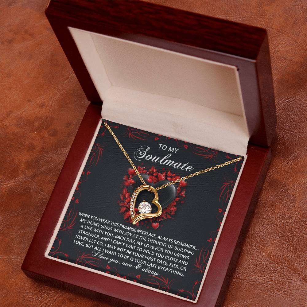 The Soulmate-Hold You Close - Forever Love Necklace, featuring a heart-shaped pendant with cubic zirconia and a gold finish, rests in its box containing a heartfelt message on the lid, elegantly displayed on a brown surface.