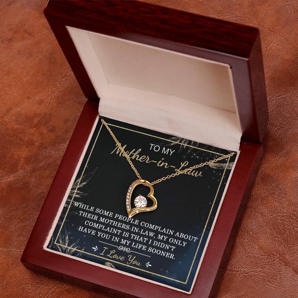 The "To Mother-In-Law, In My Life - Forever Love Necklace" features a gold finish and a cubic zirconia stone at its center. It is presented in a wooden box, with the lid reading "To my Mother-in-Law" and an inside message that expresses gratitude and love.
