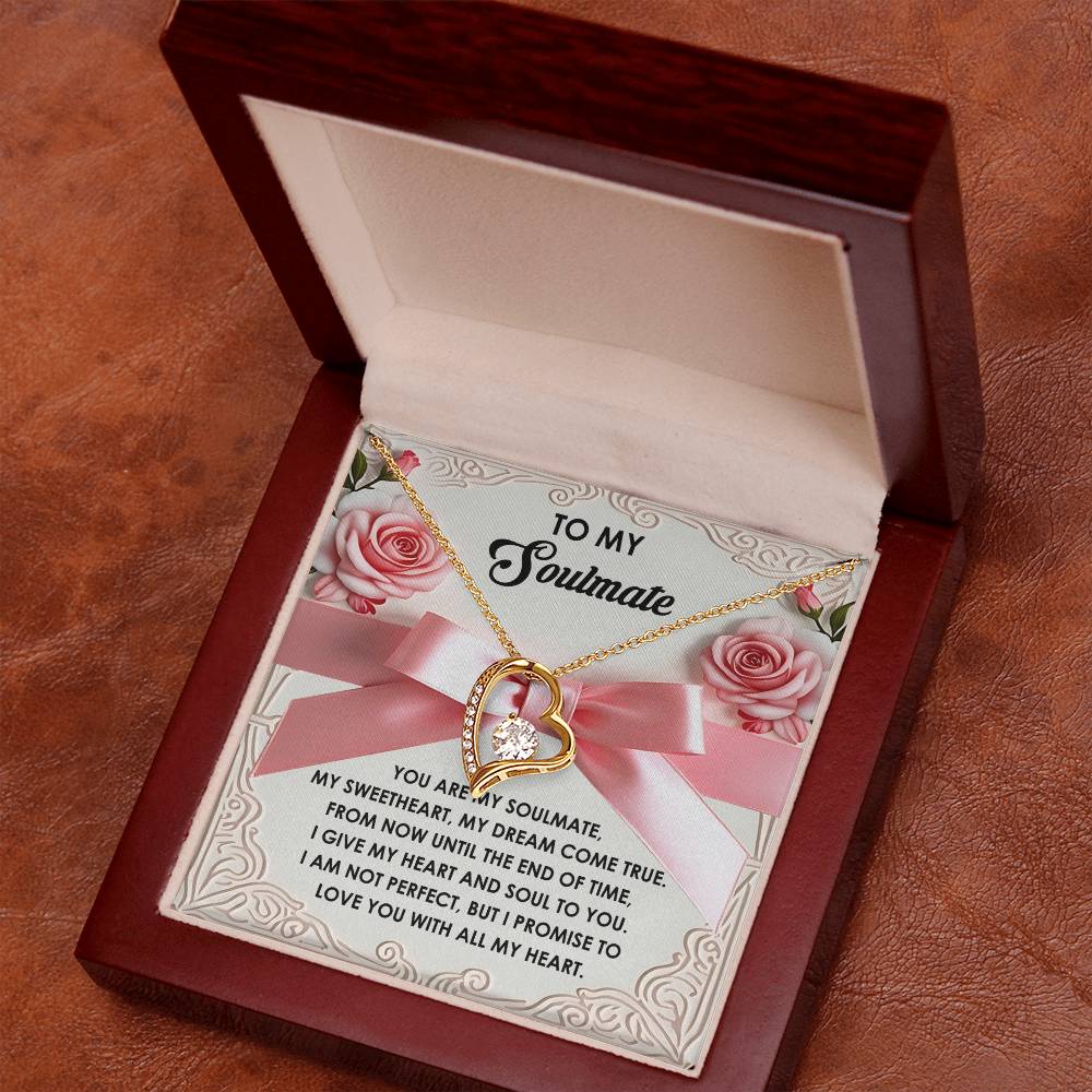 The Soulmate-Heart And Soul - Forever Love Necklace, heart-shaped and adorned with CZ crystals, sits elegantly in an open wooden box. A romantic message card is included, surrounded by pink roses and a delicate pink ribbon, enhancing its exquisite gold finish.