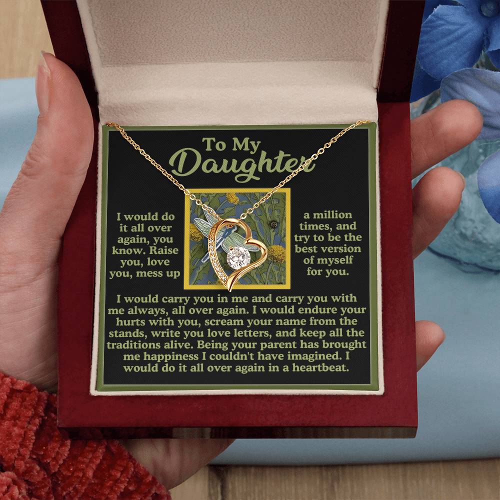 A hand holds an open jewelry box, revealing a stunning Daughter-All Over Again - Forever Love Necklace with a white gold finish and a sparkling cubic zirconia stone. The box's lid displays a heartfelt message addressed to a daughter.