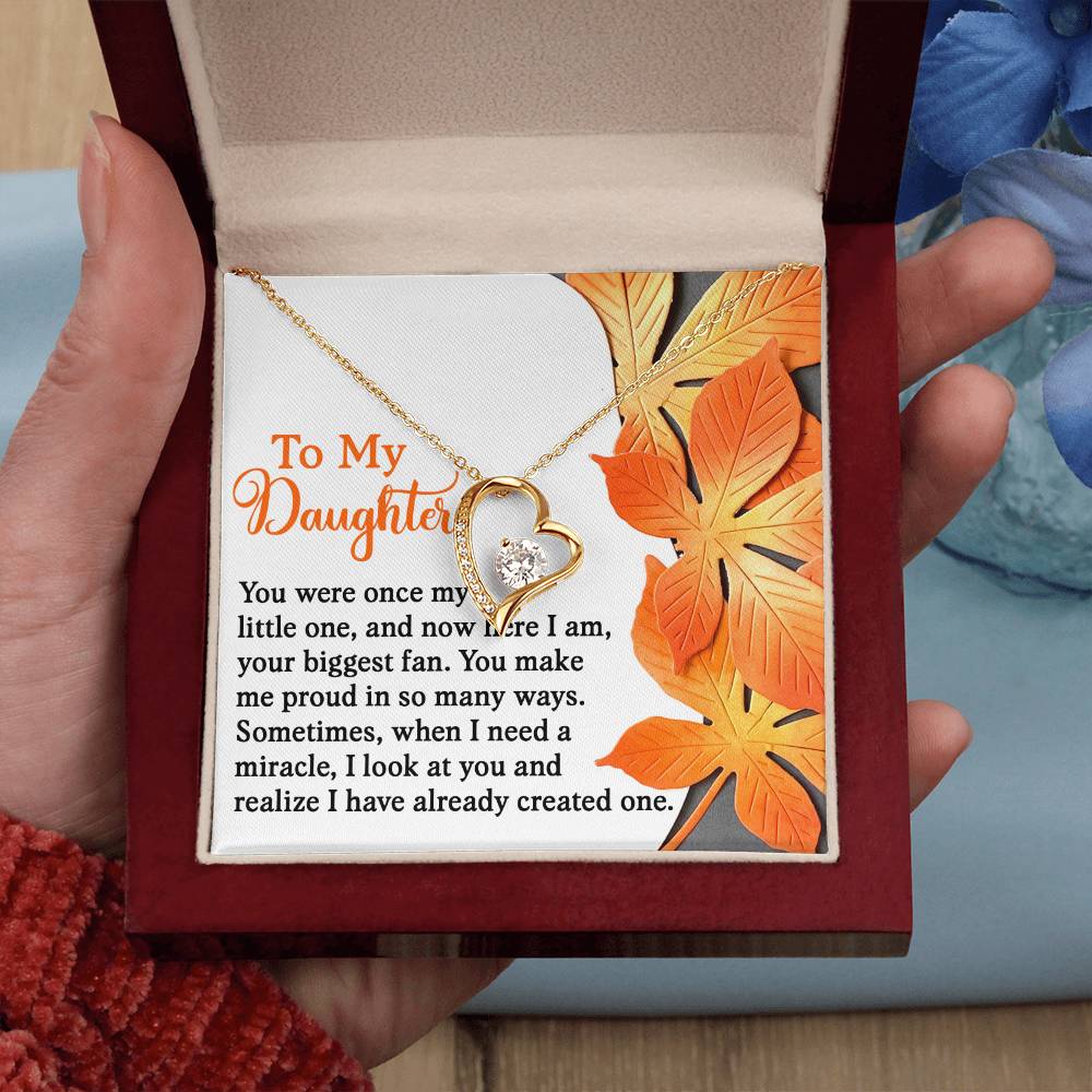 A Daughter-Here I Am - Forever Love Necklace featuring a gold finish and cubic zirconia is nestled inside a box embellished with a touching message to a daughter, encircled by lively orange leaves.