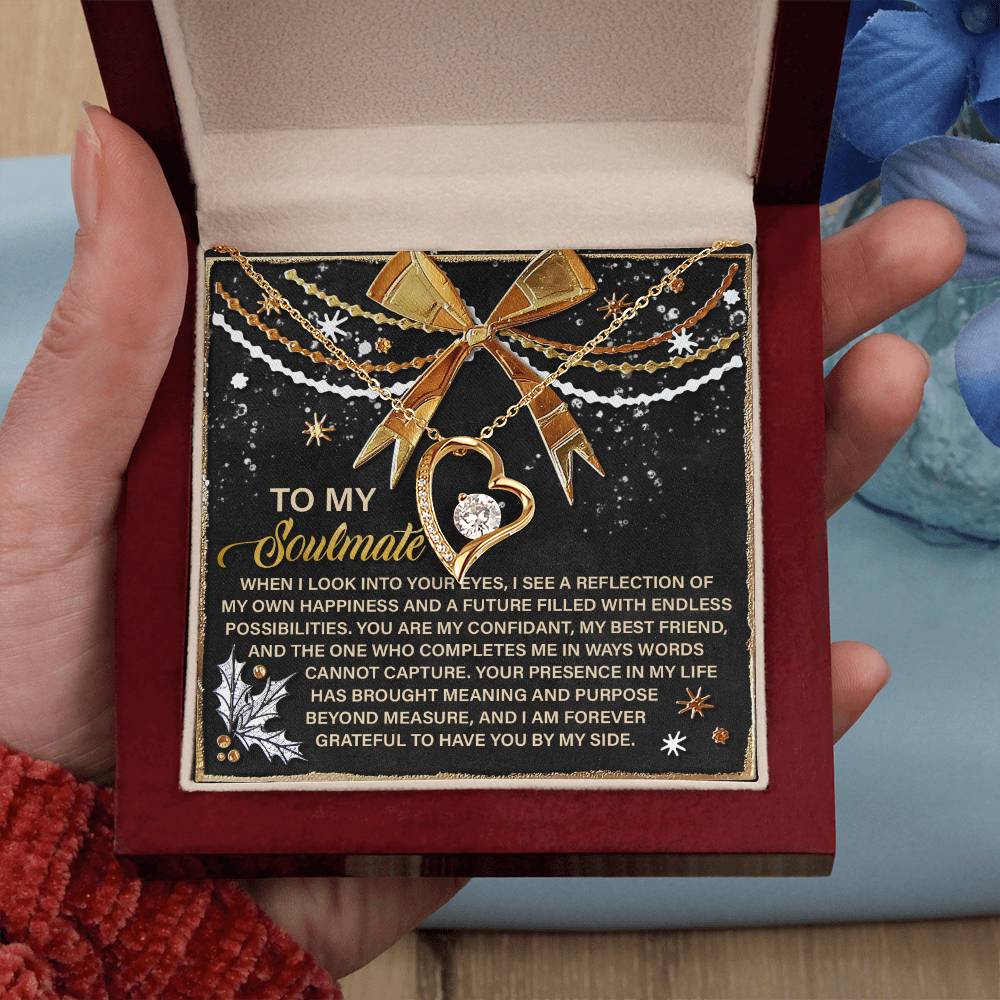A person holds an open jewelry box showing a Soulmate-By My Side - Forever Love Necklace with a heart pendant. The black interior reads "To My Soulmate," accompanied by a heartfelt message in gold and white, making it the perfect personalized gift.