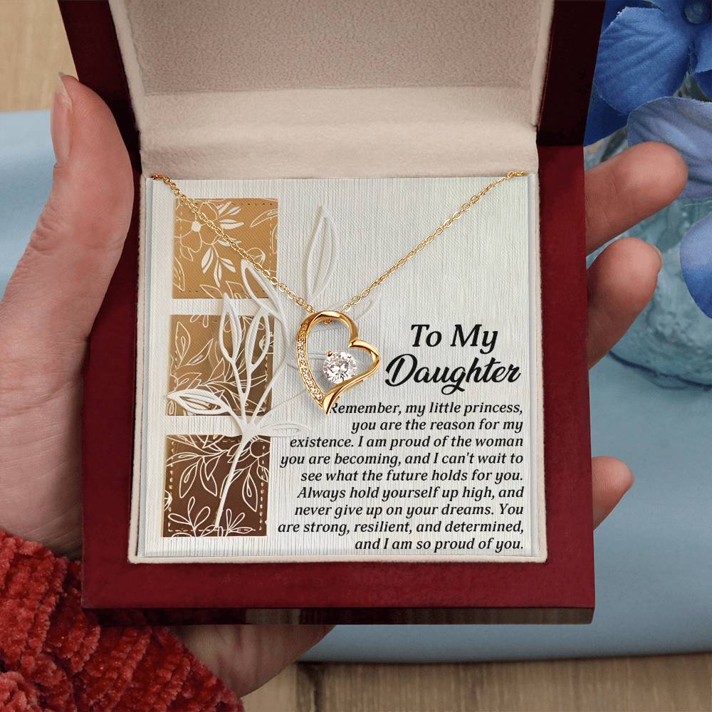 A hand presents an open jewelry box unveiling the Daughter-Holds For You - Forever Love Necklace, featuring a heart-shaped pendant embellished with a diamond and an inspirational message for a daughter. The necklace shines with a radiant gold finish, symbolizing the profound essence of eternal love.