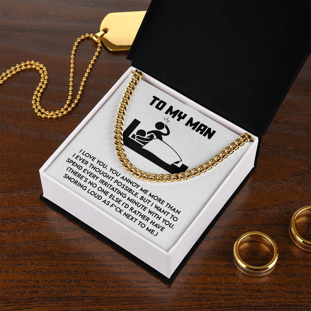 The "My Man-Next To Me - Cuban Link Chain" necklace in polished stainless steel is displayed in an open black box with a humorous message card and two gold rings resting on a wooden table.