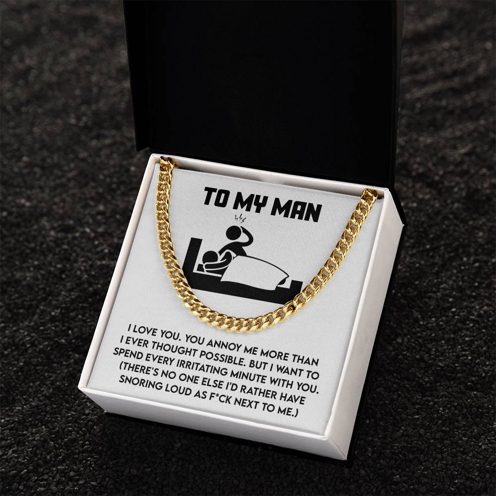 The "My Man-Next To Me" Cuban Link Chain, made of 14K yellow gold, elegantly rests in an open box. It features a humorous message about love and annoyance—an ideal gift for those who cherish wit with their precious keepsakes.