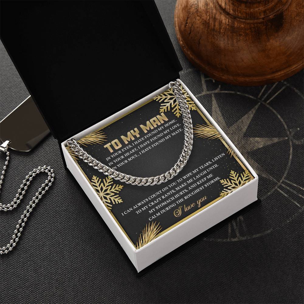 A My Man-Found My Home - Cuban Link Chain necklace is elegantly displayed in an open box, accompanied by a card that says "To My Man" with a heartfelt message. Nearby, a metallic dog tag and a wooden piece add to the perfect personalized gift scene.