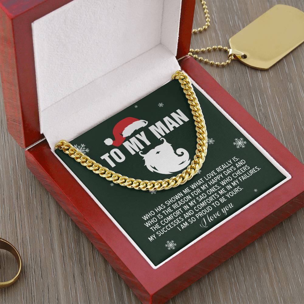 The "My Man-To Be Yours" Cuban Link Chain necklace, crafted from polished stainless steel, rests elegantly in a red velvet box. Inside, there's a card labeled "To My Man," featuring a Christmas goat motif and a heartfelt message. Nearby are a gold dog tag and an adjustable ring.