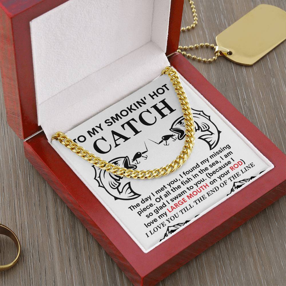 The Man-On Your Rod - Cuban Link Chain in polished gold stainless steel rests elegantly in a red jewelry box with a romantic fishing-themed card, while a gold dog tag and ring add charm on a rustic wooden surface.
