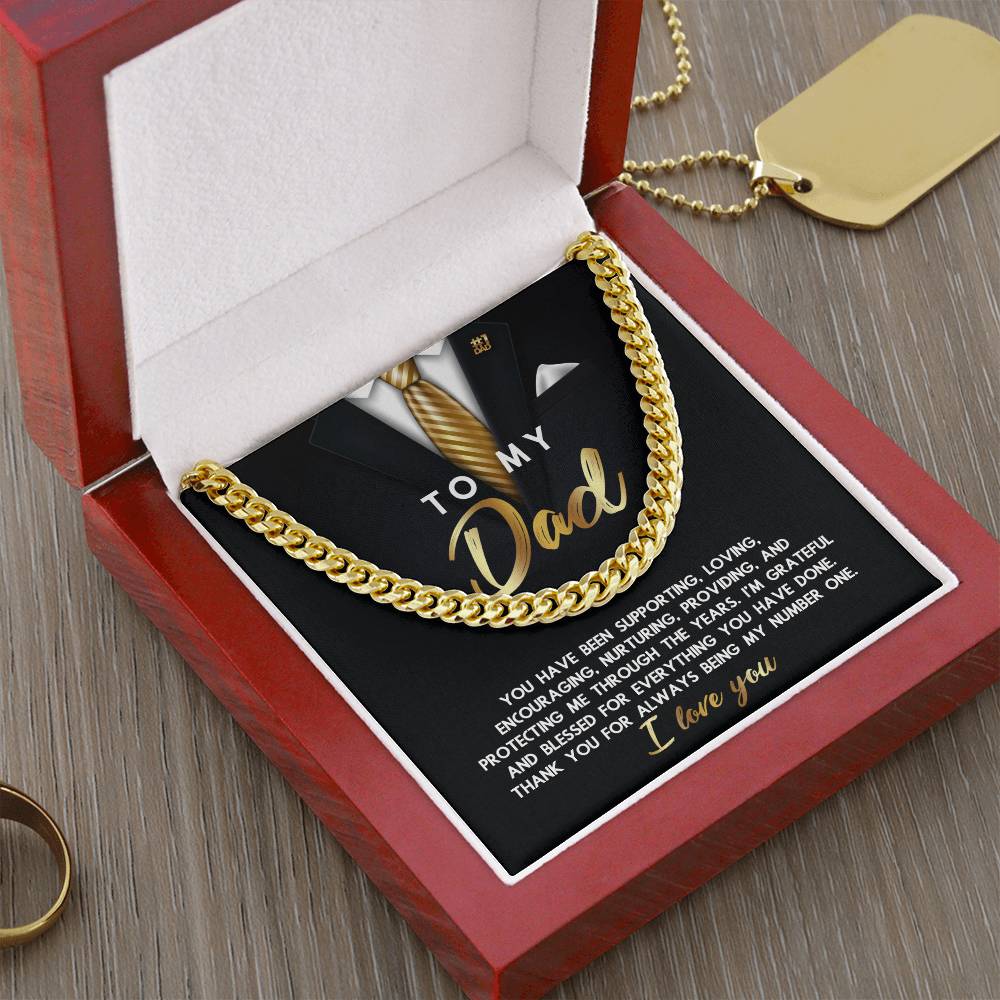 Gift this distinguished "To Dad, Through The Years - Cuban Link Chain," showcased in an open red box with a heartfelt message card. It features a suit graphic and gold chain illustration, all beautifully arranged on a wooden surface.