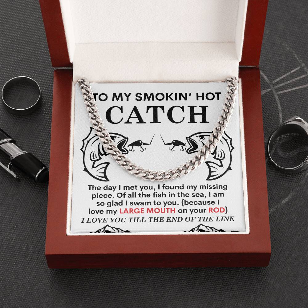 Open jewelry box revealing "The Man-On Your Rod - Cuban Link Chain" in polished stainless steel. The lid is inscribed with "To my smokin' hot catch" above a decorative design and playful text.