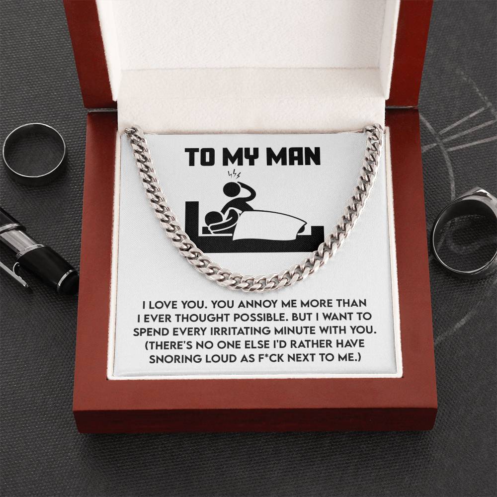 The "My Man-Next To Me - Cuban Link Chain" is a polished stainless steel necklace presented in an open box. Inside, a message reads: "To My Man" alongside a humorous note about love and snoring, with rings placed beside the box.