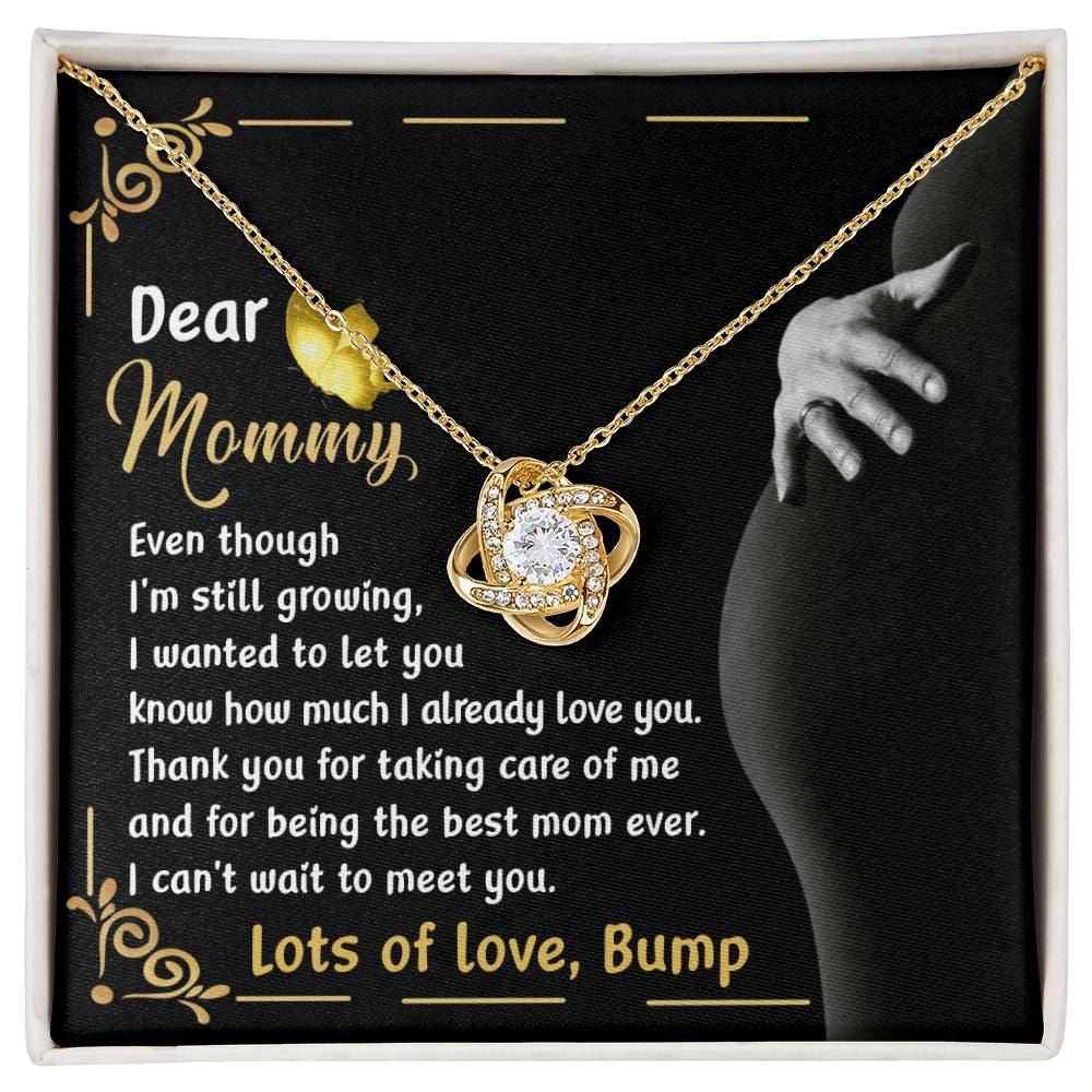 Introducing the "To Mama To Be, Best Mom Ever - Love Knot Necklace" featuring a floral pendant and cubic zirconia crystals. This exquisite piece comes on a decorative card with a heartfelt message from an unborn child to their mother, expressing love and anticipation for meeting her. Available in your choice of white gold or yellow gold finish.