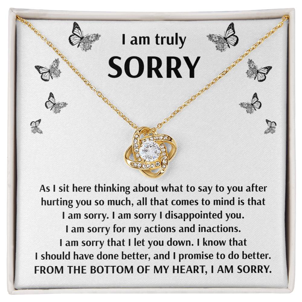 The "Sorry-Done Better" Love Knot Necklace features a beautiful gold pendant with intertwined hearts and sparkling cubic zirconia crystals, paired with an apology note adorned with butterfly motifs, expressing heartfelt regret and a promise to improve.