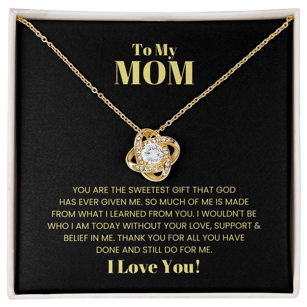 The "To My Mom, You Are The Sweetest Gift - Love Knot Necklace," adorned with premium cubic zirconia crystals, is displayed in a box with a heartfelt message that says, "To My Mom, You are the sweetest gift that God has ever given me...
