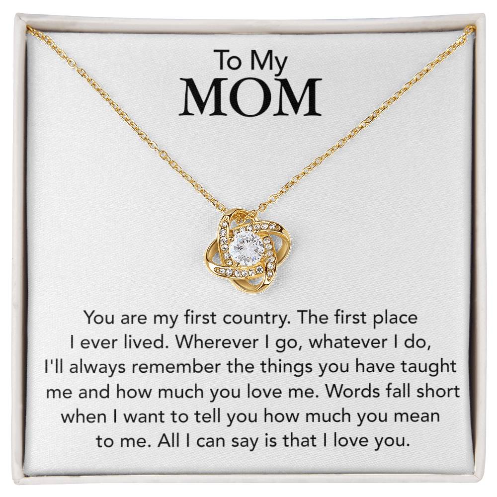 A gold heart-shaped To My Mom, You Are My First Country - Love Knot Necklace expressing love and appreciation, showcased in a square frame by ShineOn Fulfillment.