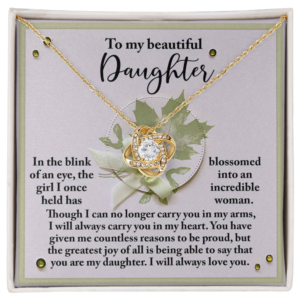The Daughter-Incredible Woman Love Knot Necklace, adorned with cubic zirconia crystals, is displayed on a card containing a heartfelt message addressed to a daughter, expressing pride and love.