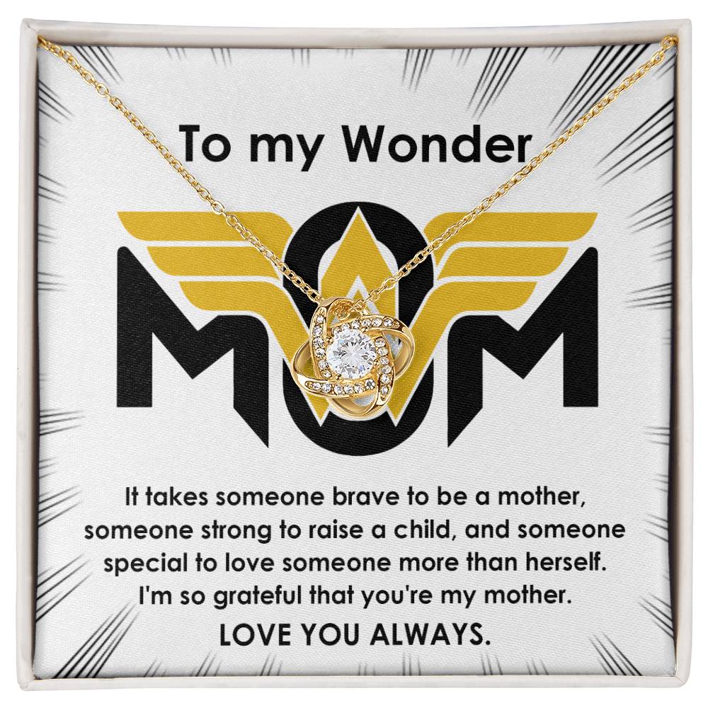 The "To Mom, More Than Herself" Love Knot Necklace features a gold pendant adorned with sparkling cubic zirconia crystals, elegantly presented on a card that reads, "To my Wonder MOM" and includes a heartfelt message about mothers.
