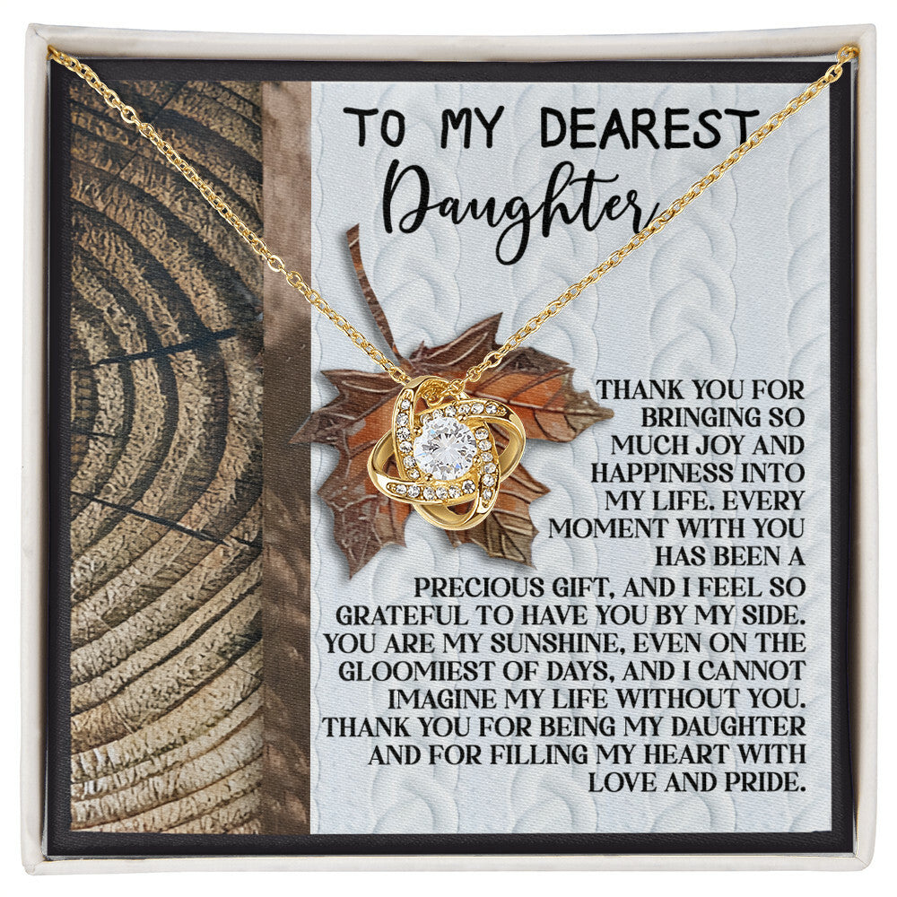 The Daughter-Love And Pride - Love Knot Necklace, featuring a gold heart-shaped pendant adorned with cubic zirconia crystals, is presented in a box alongside a thank-you message for your daughter. This heartfelt message conveys joy, gratitude, and love, making this personalized gift a perfect expression of your deepest sentiments.