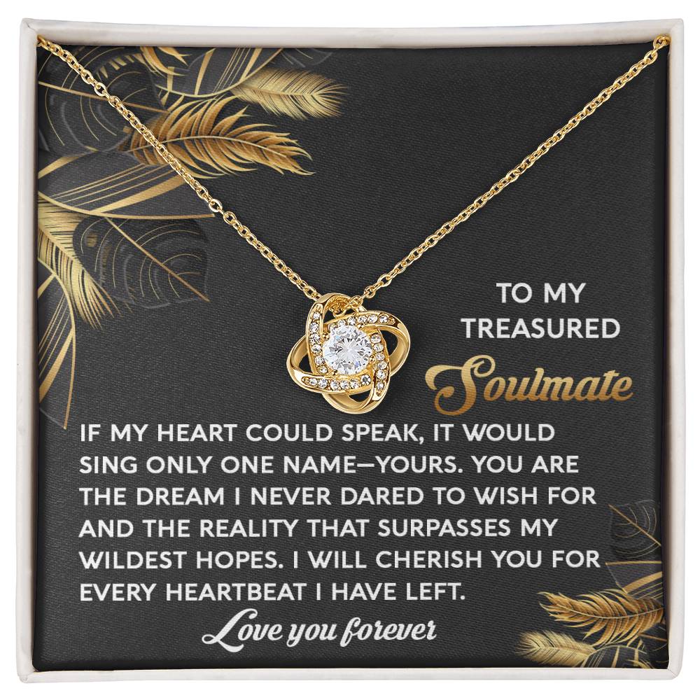 The Soulmate-Wildest Hopes Love Knot Necklace boasts a dazzling cubic zirconia crystal pendant. It comes on a card adorned with leaf designs and heartfelt soulmate messages, ending with "Love you forever." A timeless yellow gold finish enhances its elegant allure.