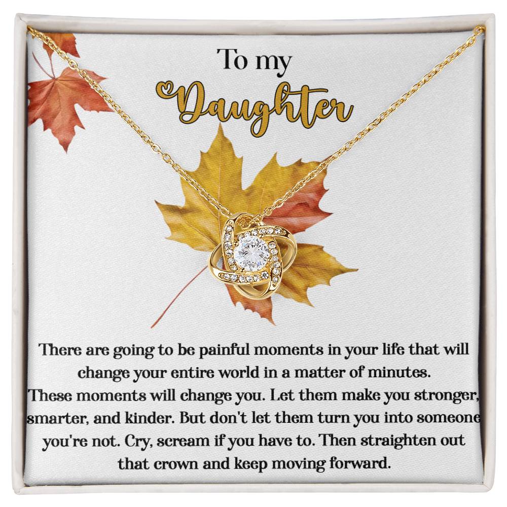The Daughter-Make You Stronger - Love Knot Necklace features a heartfelt message on the box: "To my Daughter. There are going to be painful moments in your life that will change your entire world in a matter of minutes..." and is beautifully presented with autumn leaves in the background. The necklace itself showcases a stunning 14k white gold design adorned with sparkling cubic zirconia crystals.