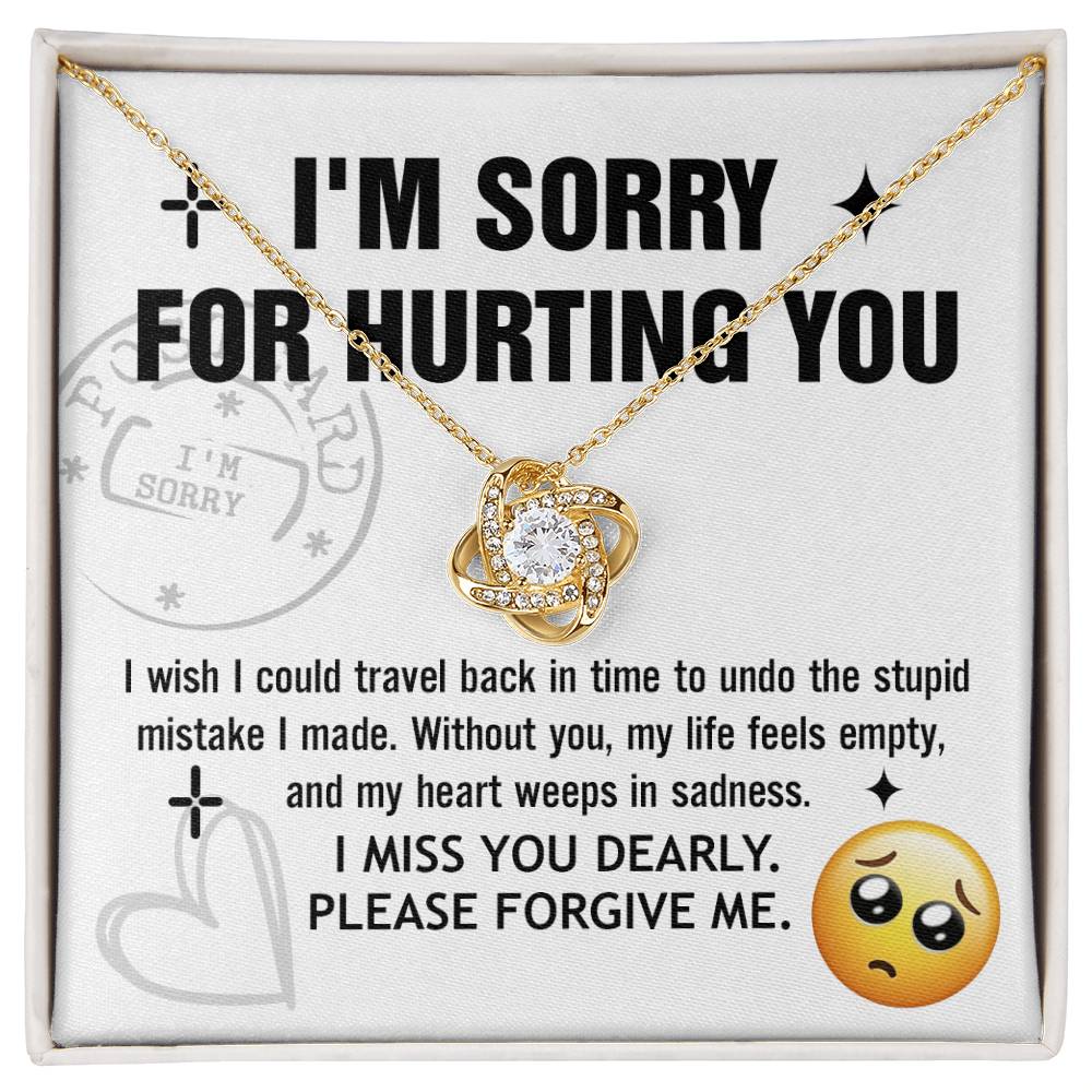 A Sorry-Travel Back - Love Knot Necklace with a white gold finish is displayed on a card featuring the text: "I'M SORRY FOR HURTING YOU," along with an apology note and a sad face emoji at the bottom right.