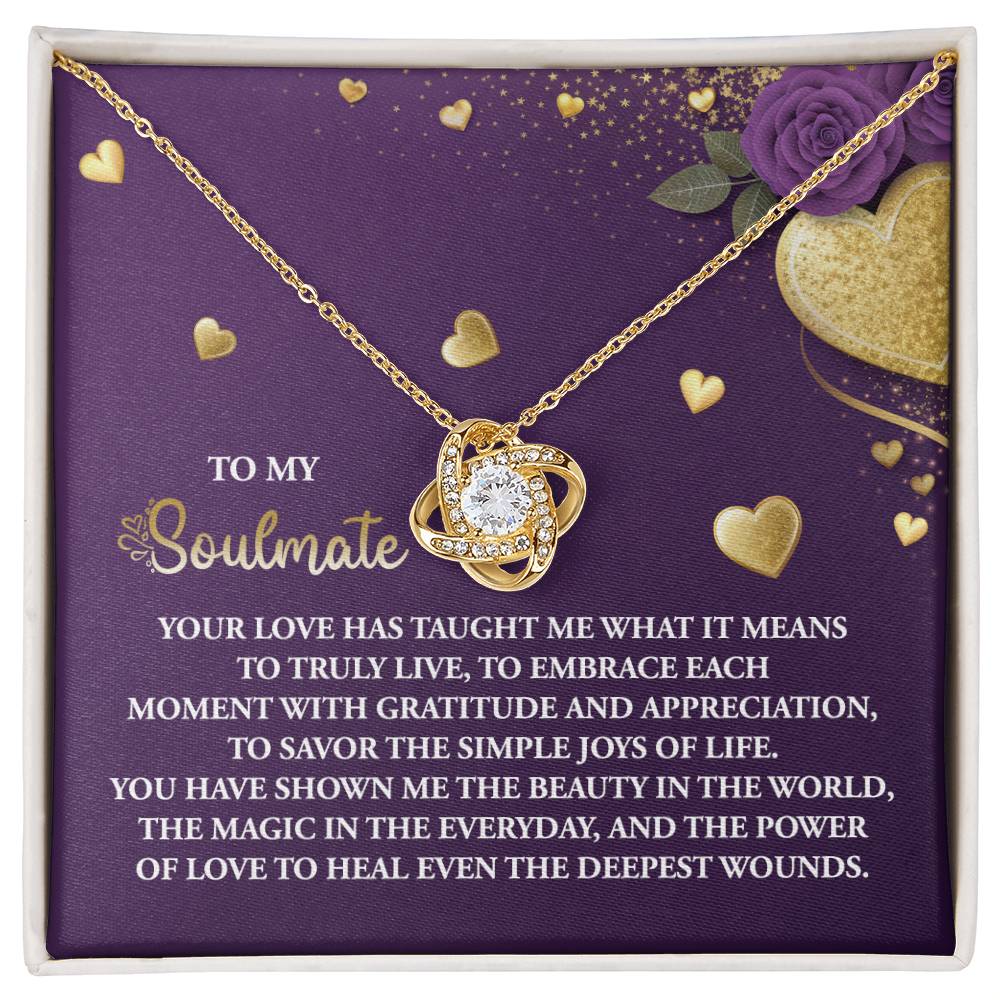 The Soulmate-Joys Of Life love knot necklace features a crystal pendant with a gold finish, elegantly displayed on a purple card with a romantic message about love for added sentimentality.