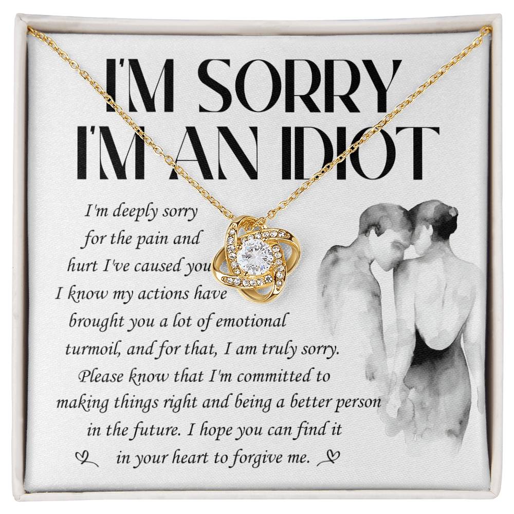 The Sorry-Emotional Turmoil - Love Knot Necklace features a heart-shaped pendant adorned with cubic zirconia crystals and comes presented on a card that reads "I'M SORRY I'M AN IDIOT" along with an apology message, accompanied by an illustration of a couple embracing. This elegant necklace is available in either white gold or yellow gold finish.