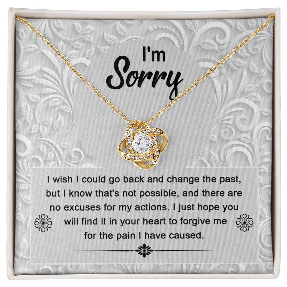 The Sorry-Change The Past - Love Knot Necklace with a white gold finish sits in a box with an apology message that reads, "I'm Sorry. I wish I could go back and change the past... I just hope you will find it in your heart to forgive me." The pendant sparkles with cubic zirconia crystals, symbolizing the unbreakable bond of love.