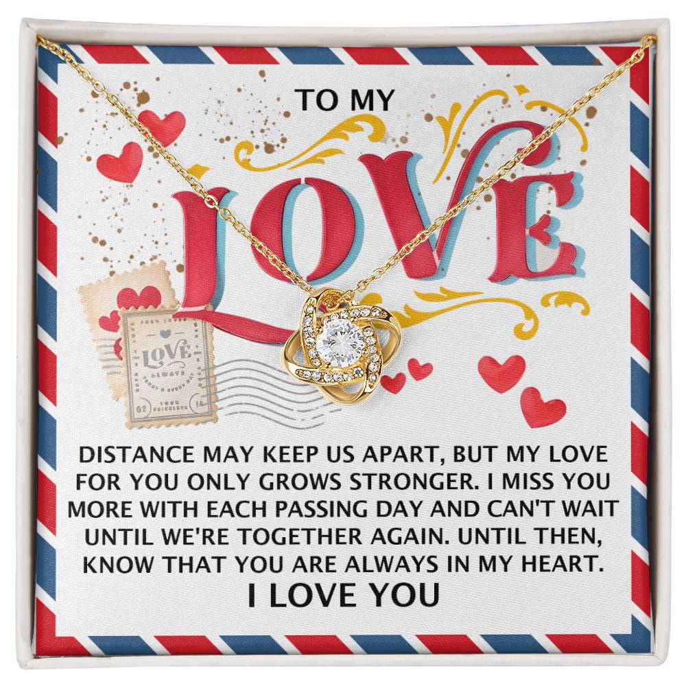 The Soulmate-In My Heart - Love Knot Necklace, made of 14k white gold and set against a "LOVE" backdrop with a touching message on enduring affection, features a pendant adorned with radiant cubic zirconia crystals symbolizing love's resilience despite distance.