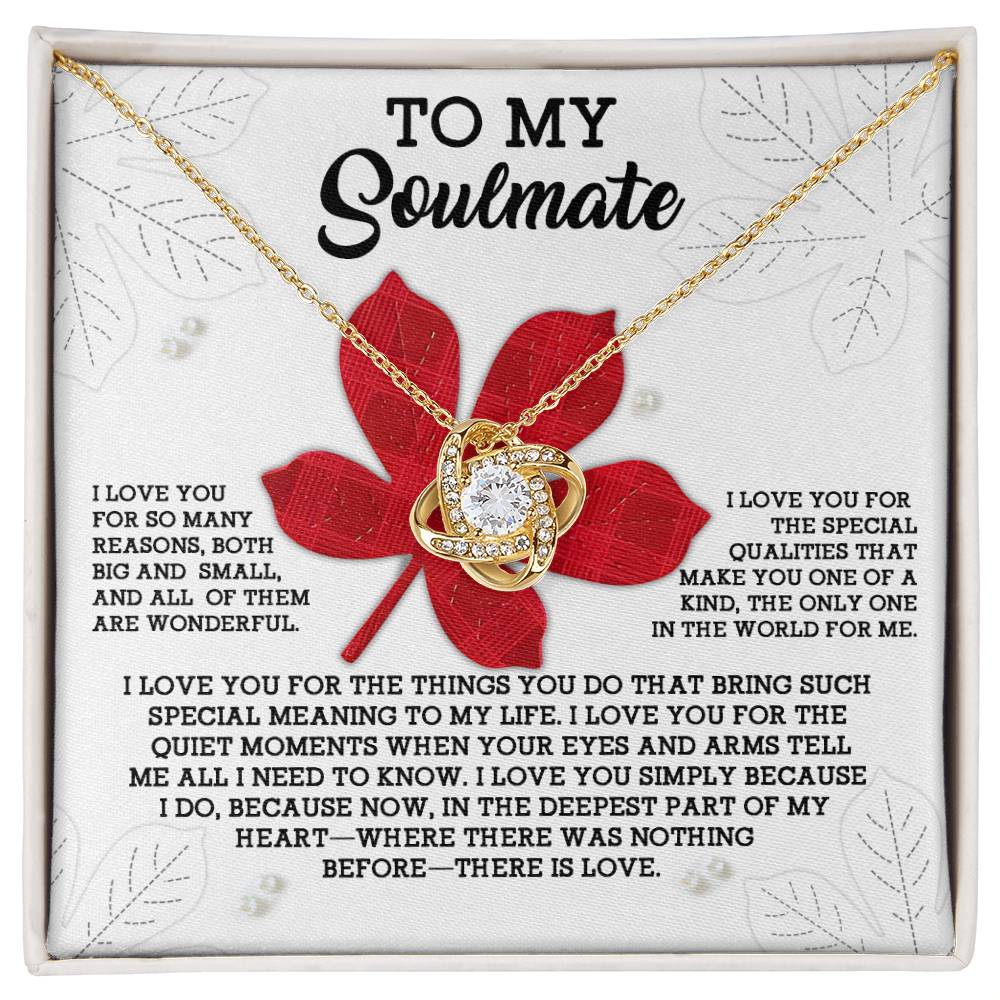 The Soulmate-There Is Love - Love Knot Necklace, with its gold finish and intertwined heart and infinity symbol pendant adorned with cubic zirconia crystals, gracefully rests on a card that reads "To My Soulmate" along with a heartfelt message against a red leaf background.