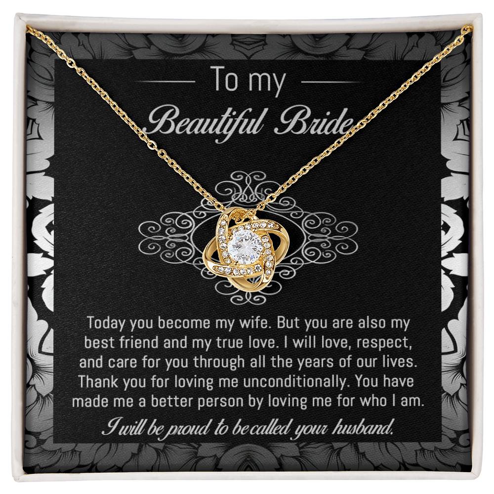 The "To Bride, My True Love - Love Knot Necklace" with a diamond pendant is displayed in a black and white box adorned with a floral pattern. The box, featuring cubic zirconia crystals, includes a heartfelt message addressed to "my beautiful bride" from her husband.