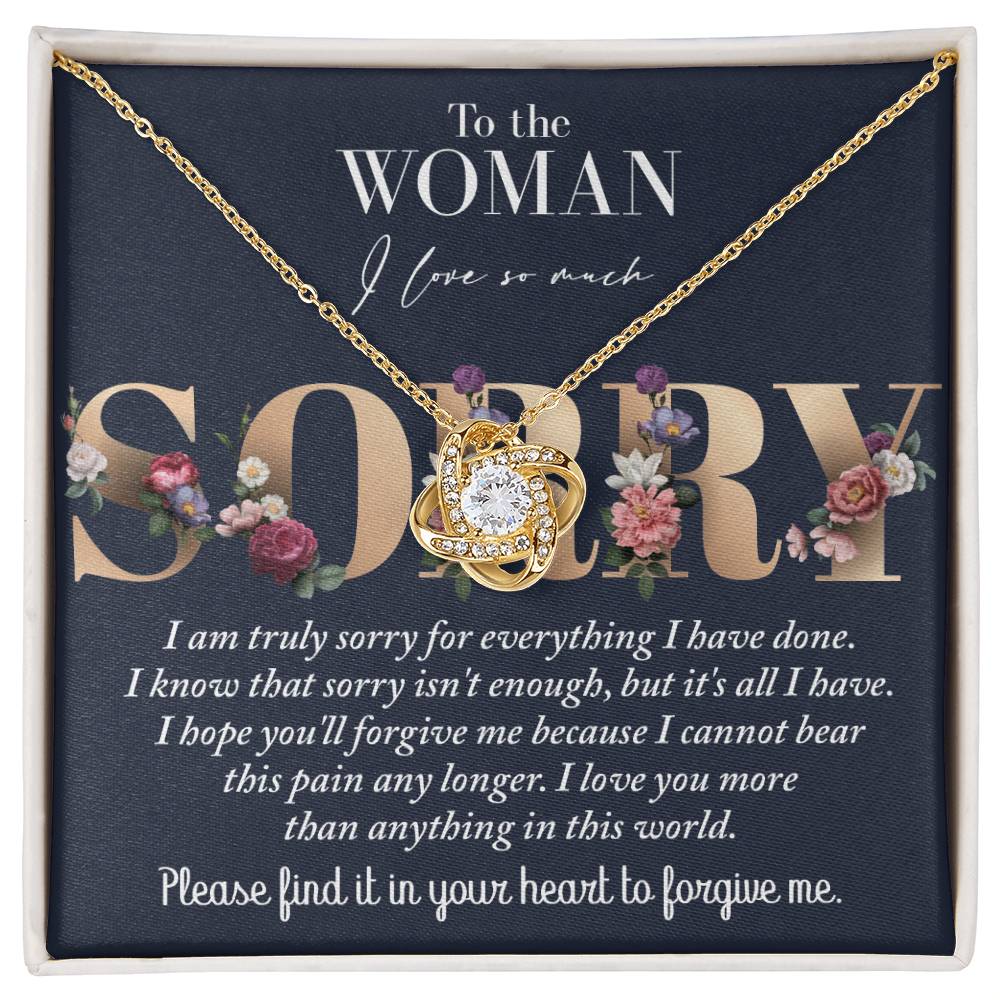 The "Sorry-Bear This Pain - Love Knot Necklace" features a 14k white gold Love Knot adorned with cubic zirconia crystals and is presented on a card that reads, "To the Woman I love so much SORRY," alongside an apology message.
