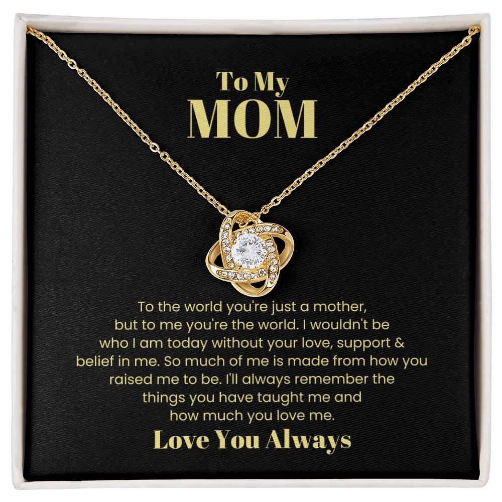 The "To My Mom, To The World You Are Just A Mother - Love Knot Necklace" features a heart-shaped pendant adorned with cubic zirconia crystals, elegantly presented in a box with a touching message about a child's love and appreciation for their mother. This personalized gift perfectly captures the heartfelt emotions shared between mother and child.