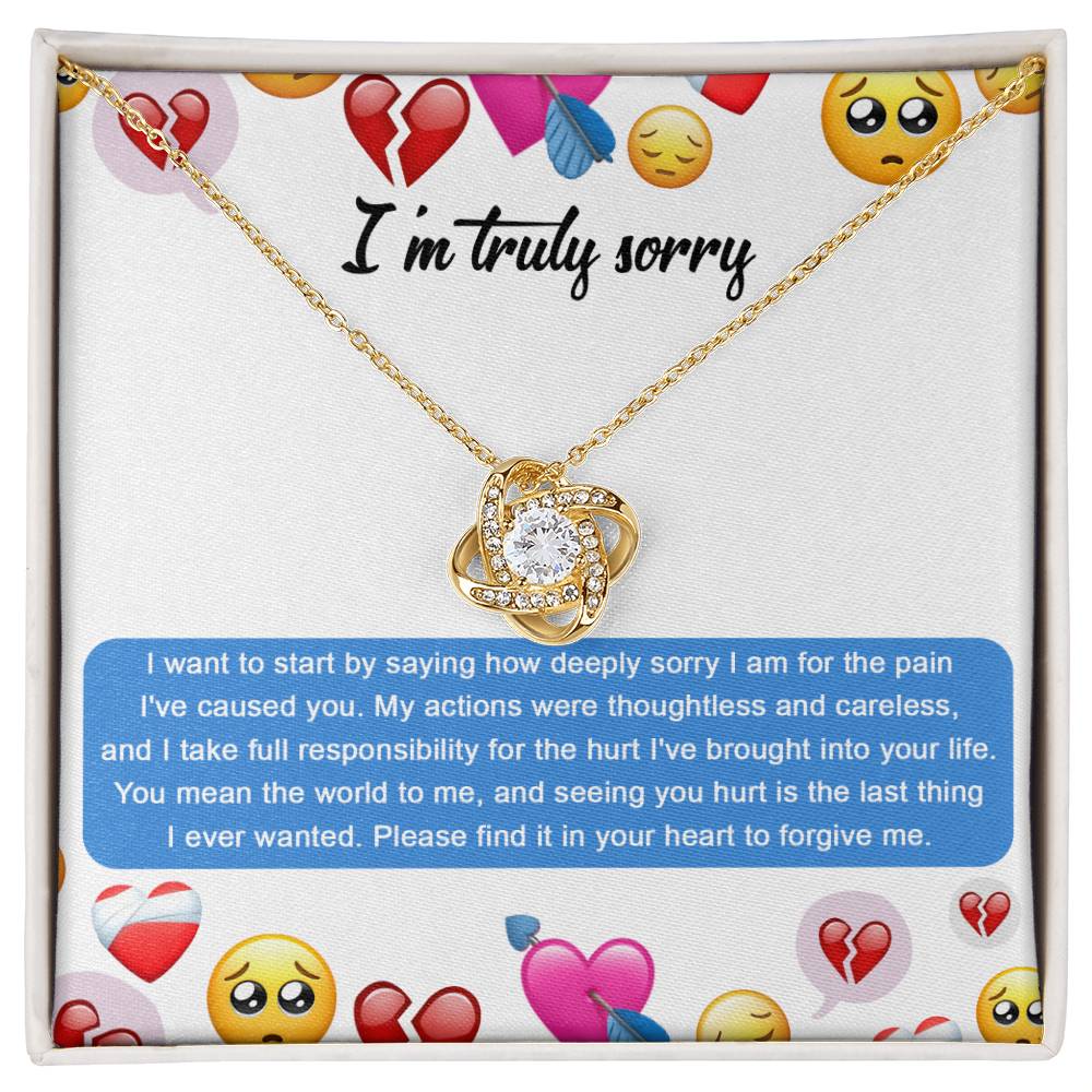 The Sorry-How Deeply Sorry - Love Knot Necklace features a pendant with an intertwined design, adorned with sparkling cubic zirconia crystals. The piece rests on a card that includes an apology message accompanied by various emoticons, such as hearts and sad faces.