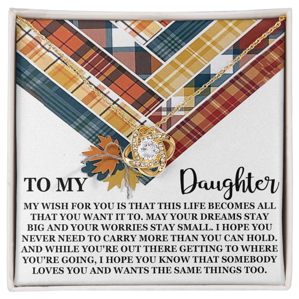 A Love Knot Necklace featuring a heart-shaped pendant adorned with Cubic Zirconia Crystals on a plaid background. Text reads: "To My Daughter, My wish for you is that this life becomes all that you want it to." and continues with a heartfelt message.